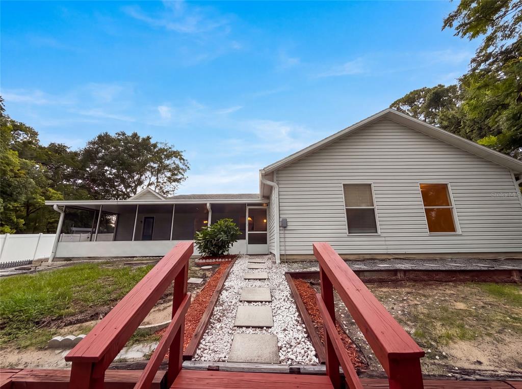 A red wooden bridge leads to a stone walkway in front of a house exterior — 29 VALENCIA CIRCLE, DEBARY, FL