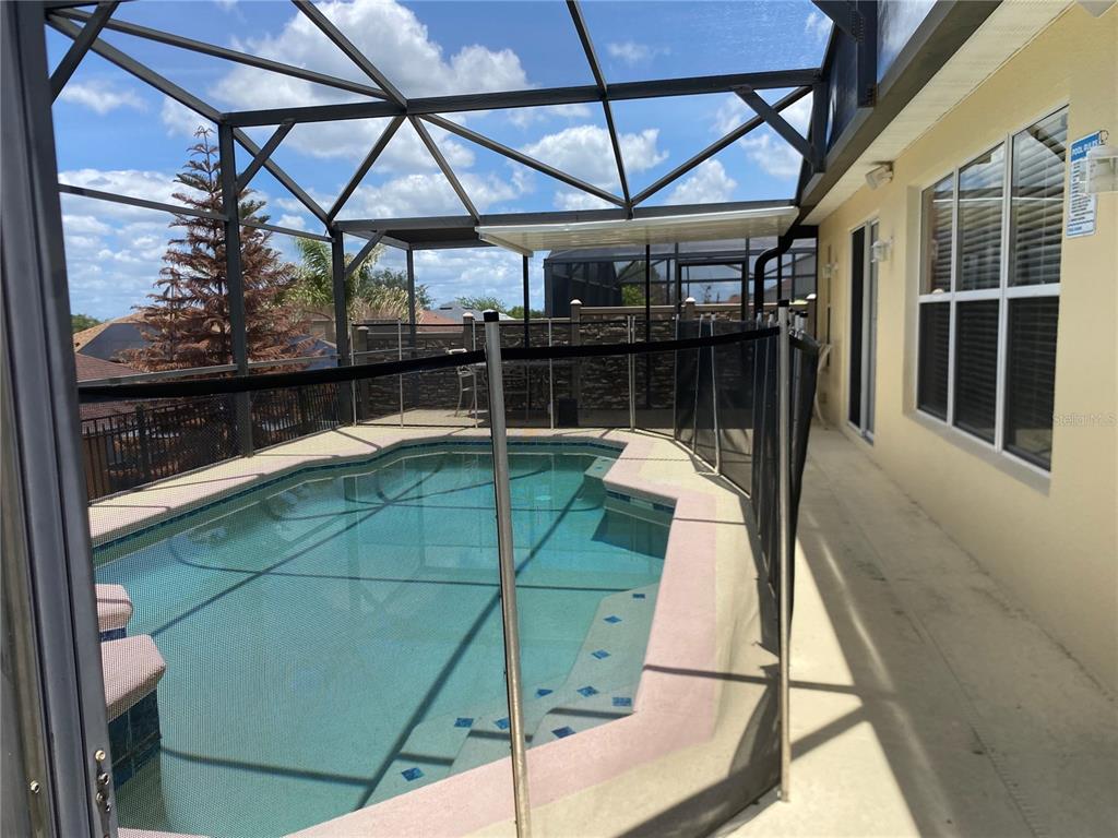 A swimming pool with a safety fence is enclosed within a screened-in lanai — 662 ROSSELLI BOULEVARD, DAVENPORT, FL