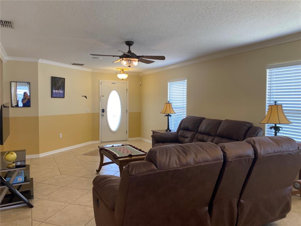 A living room features tile flooring, a ceiling fan, and a brown leather sectional sofa — 662 ROSSELLI BOULEVARD, DAVENPORT, FL
