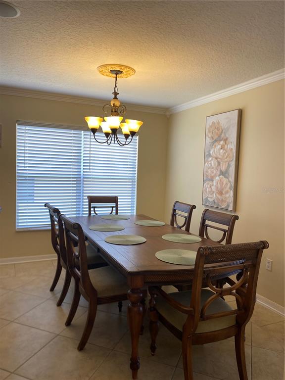 A dining room features a wooden table with six chairs, a chandelier, and wall art — 662 ROSSELLI BOULEVARD, DAVENPORT, FL