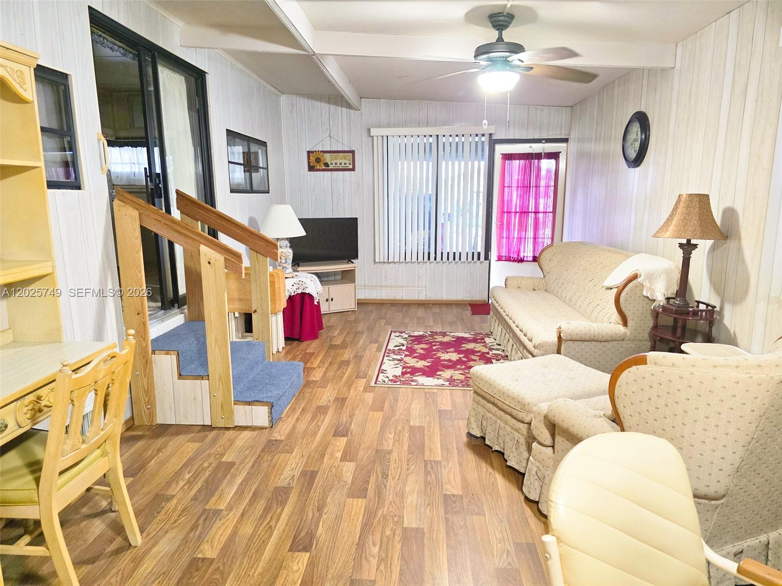 A living room features wood-look flooring, paneled walls, a ceiling fan, and a small staircase — 5302 SE 64TH TERR, Okeechobee FL 34974, OKEECHOBEE, FL