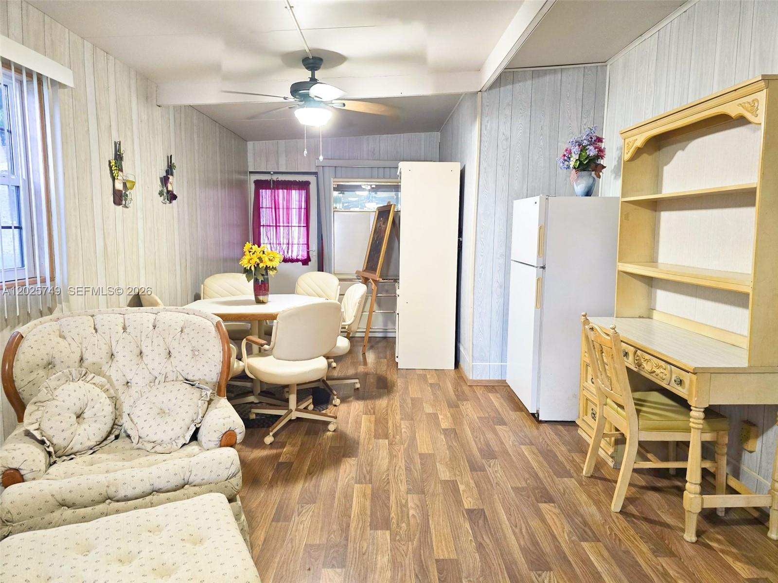 A living and dining area features wood-look flooring, paneled walls, and a ceiling fan — 5302 SE 64TH TERR, Okeechobee FL 34974, OKEECHOBEE, FL
