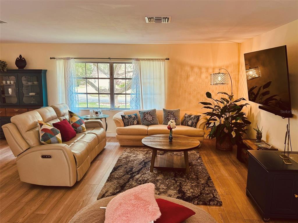 A living room features two beige sofas, a round wooden coffee table, and a television — 764 FOREST GLEN ROAD, CLEARWATER, FL