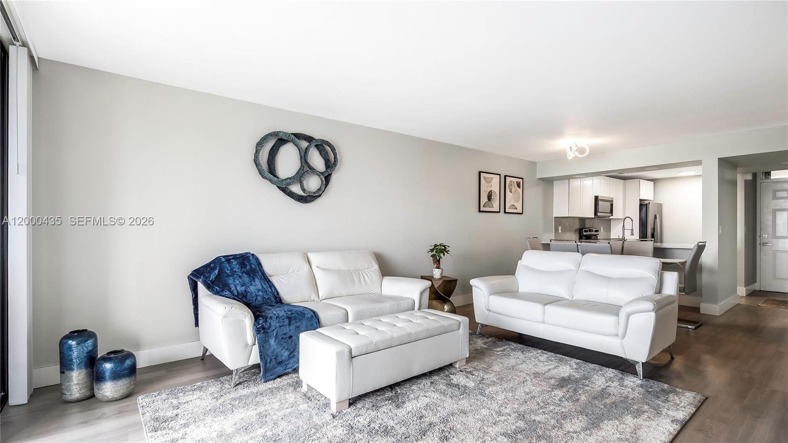 A living room features white leather sofas, a matching ottoman, and a gray area rug — 6231 Coral Lake Dr # 307, Margate FL 33063, MARGATE, FL