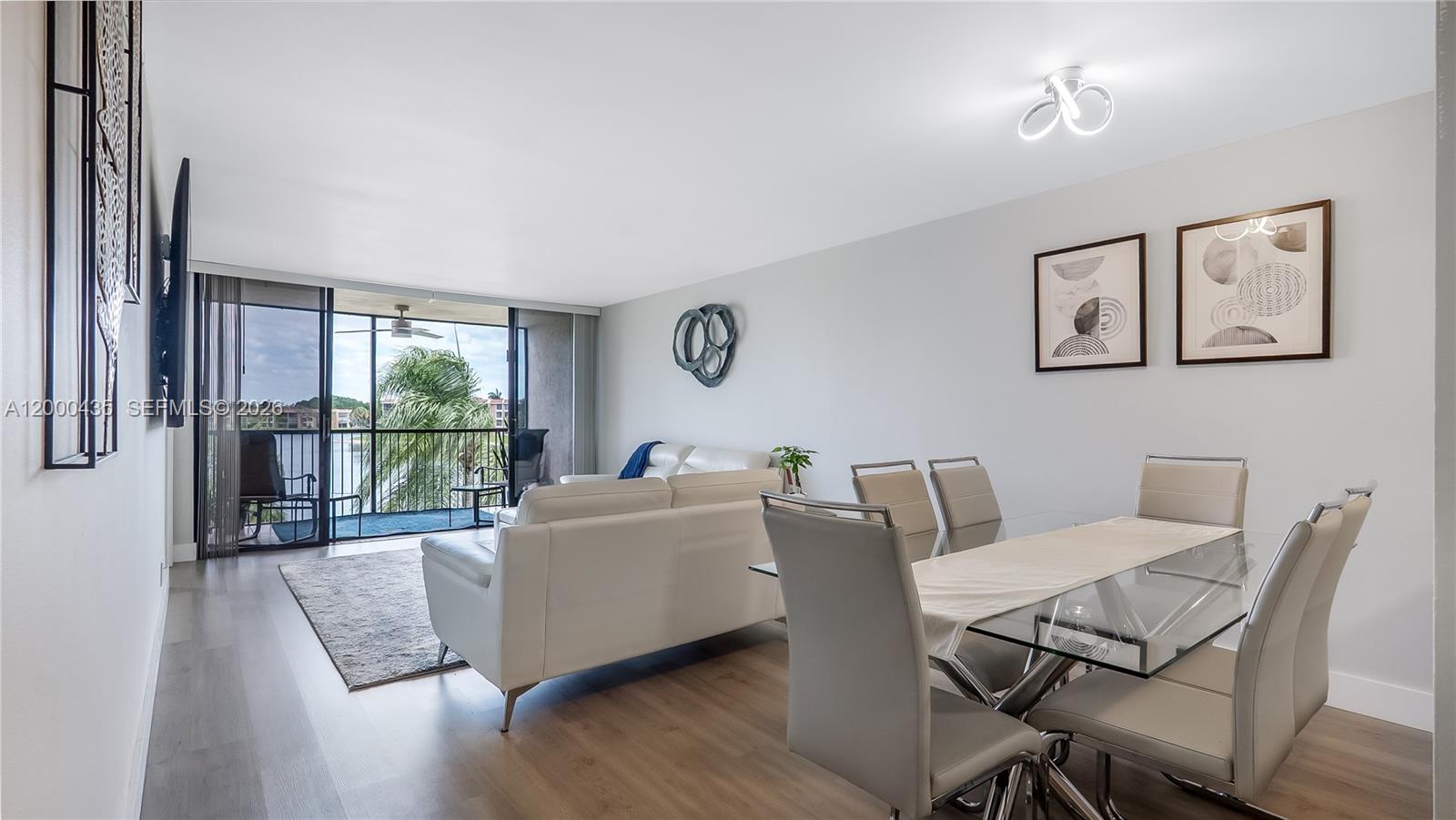 A living and dining area features light wood floors, white furniture, and a balcony view — 6231 Coral Lake Dr # 307, Margate FL 33063, MARGATE, FL