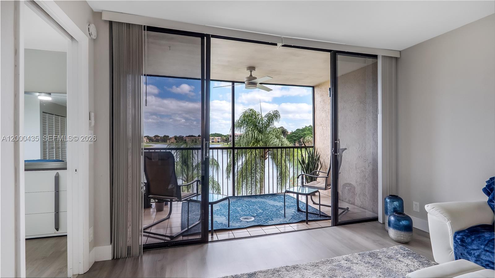 A living room opens through sliding glass doors to a screened balcony overlooking a lake — 6231 Coral Lake Dr # 307, Margate FL 33063, MARGATE, FL
