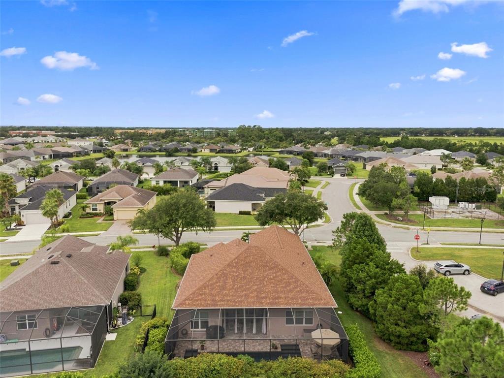 An aerial view shows a suburban house with a screened-in pool patio and brown roof — 3850 CREEKSIDE PARK DR, PARRISH, FL