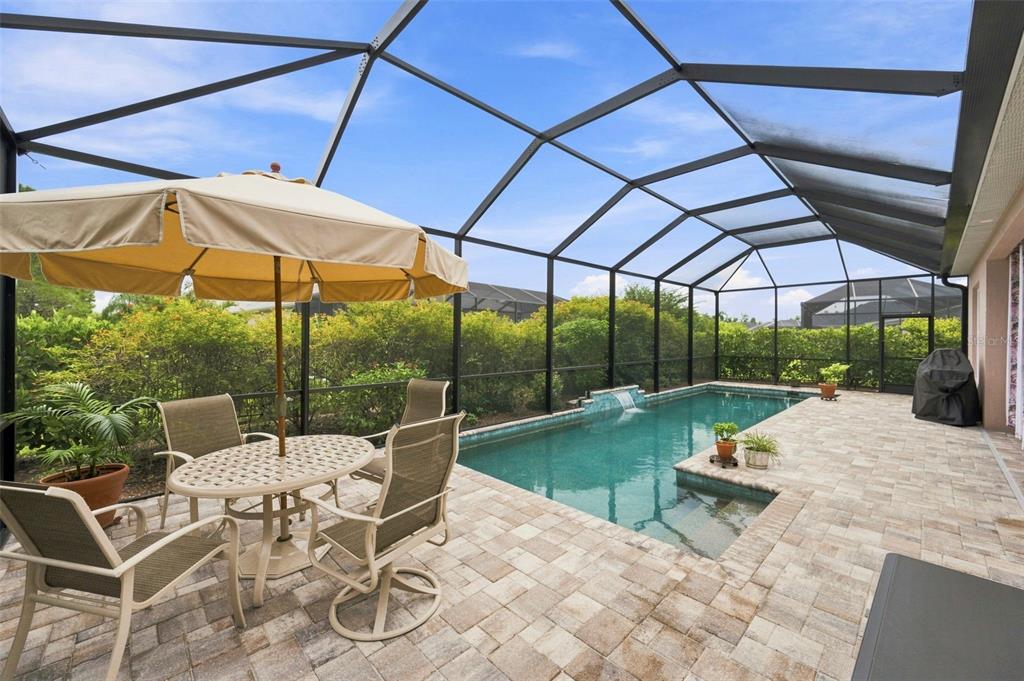 A screened-in pool patio features a dining set, a small swimming pool, and lush landscaping — 3850 CREEKSIDE PARK DR, PARRISH, FL