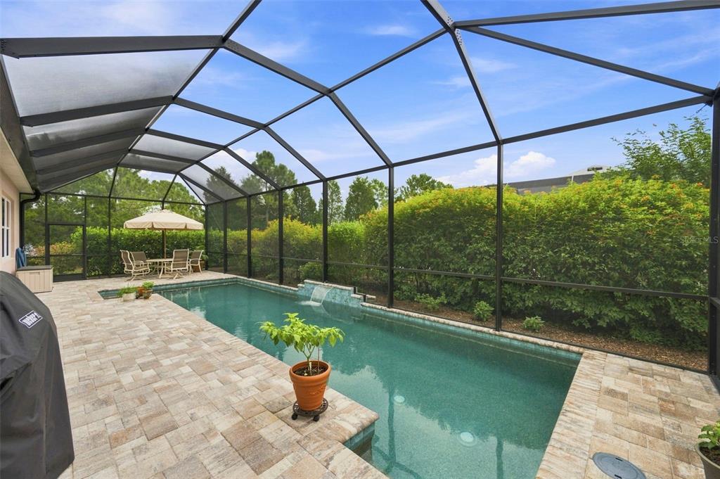 A screened-in patio features a rectangular swimming pool with a water feature and paver decking — 3850 CREEKSIDE PARK DR, PARRISH, FL