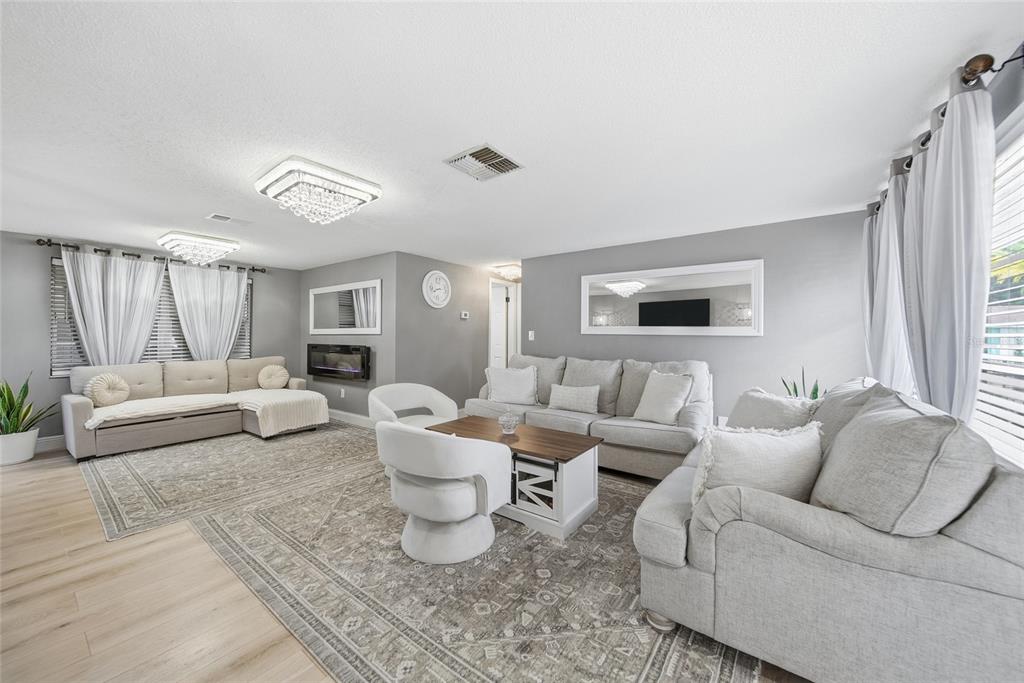 A living room features light gray walls, two sofas, two swivel chairs, and crystal chandeliers — 7435 FIRESIDE DRIVE, PORT RICHEY, FL