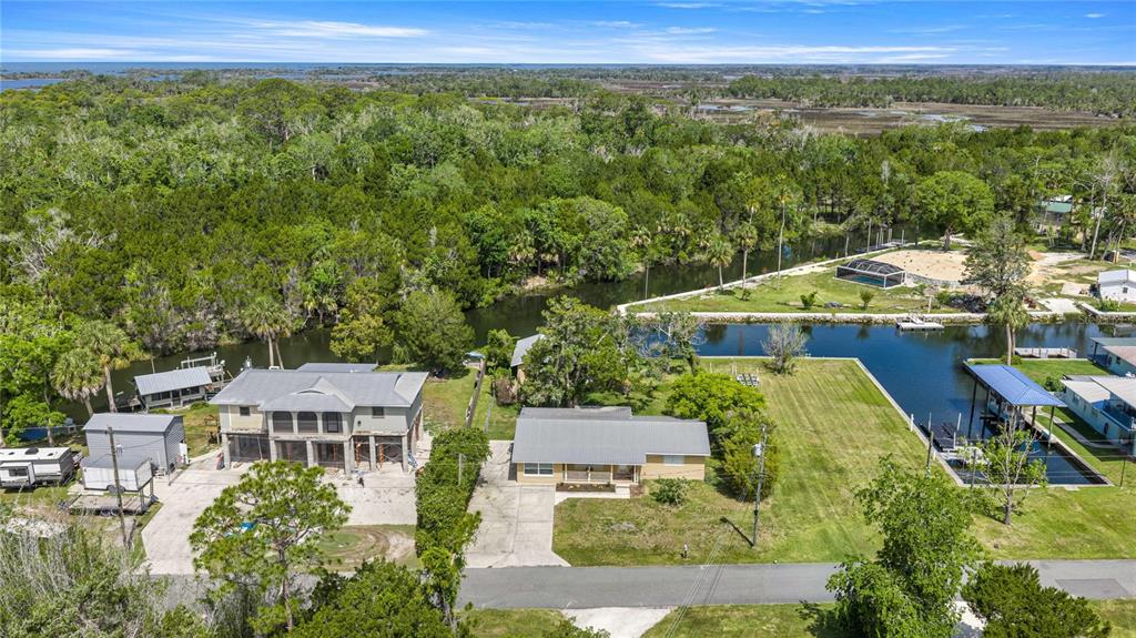 An aerial view shows two houses with metal roofs situated along a canal near trees — 46 MAGNOLIA AVENUE, YANKEETOWN, FL