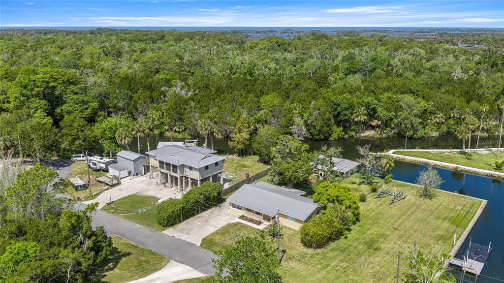 An aerial view shows two houses on a waterfront lot surrounded by dense green trees — 46 MAGNOLIA AVENUE, YANKEETOWN, FL