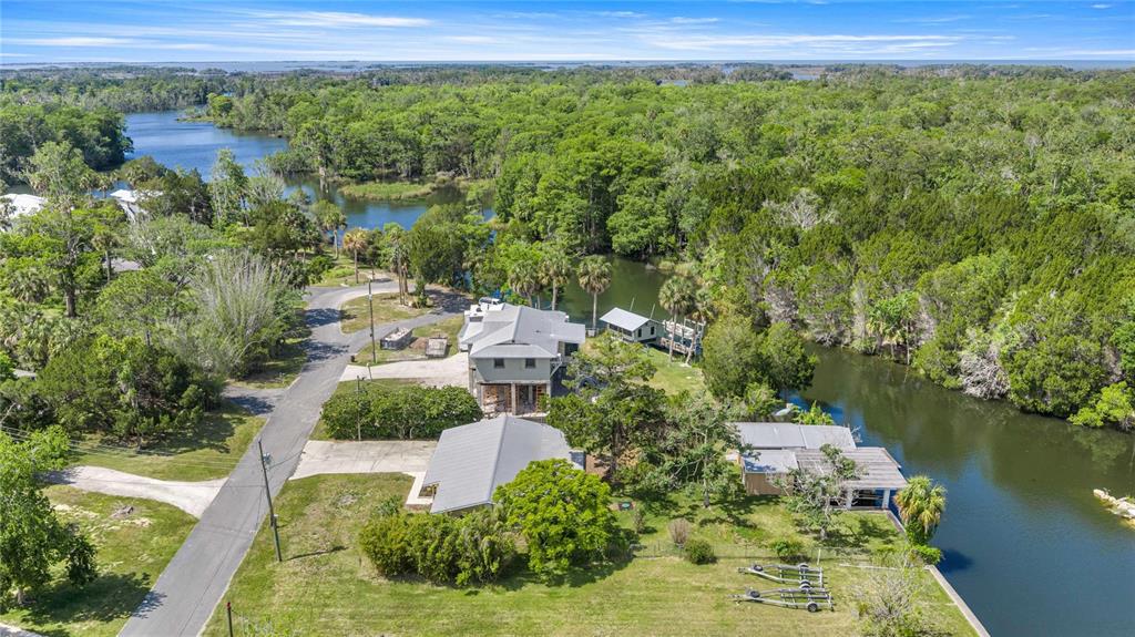 An aerial view shows a house with a metal roof situated near a winding river — 46 MAGNOLIA AVENUE, YANKEETOWN, FL
