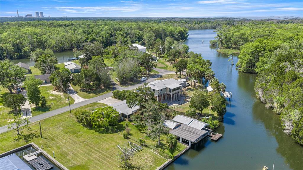 An aerial view shows waterfront houses along a canal surrounded by dense green trees — 46 MAGNOLIA AVENUE, YANKEETOWN, FL