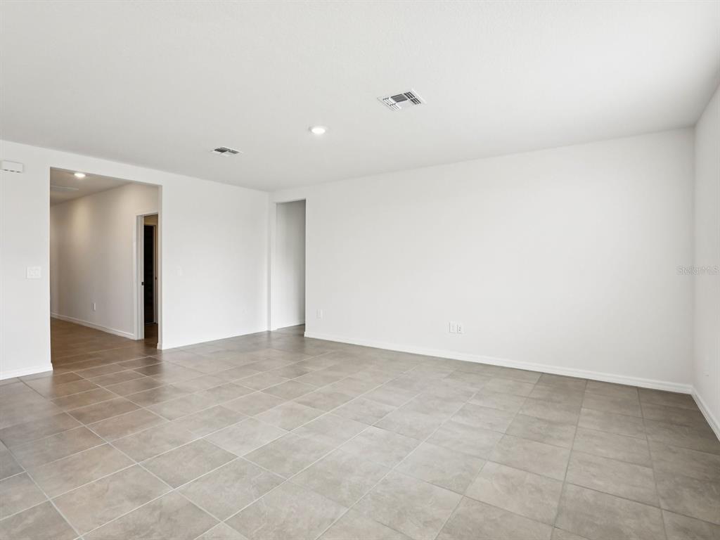 An empty room with white walls and large gray floor tiles — 1785 FOREST RUN LANE, AUBURNDALE, FL