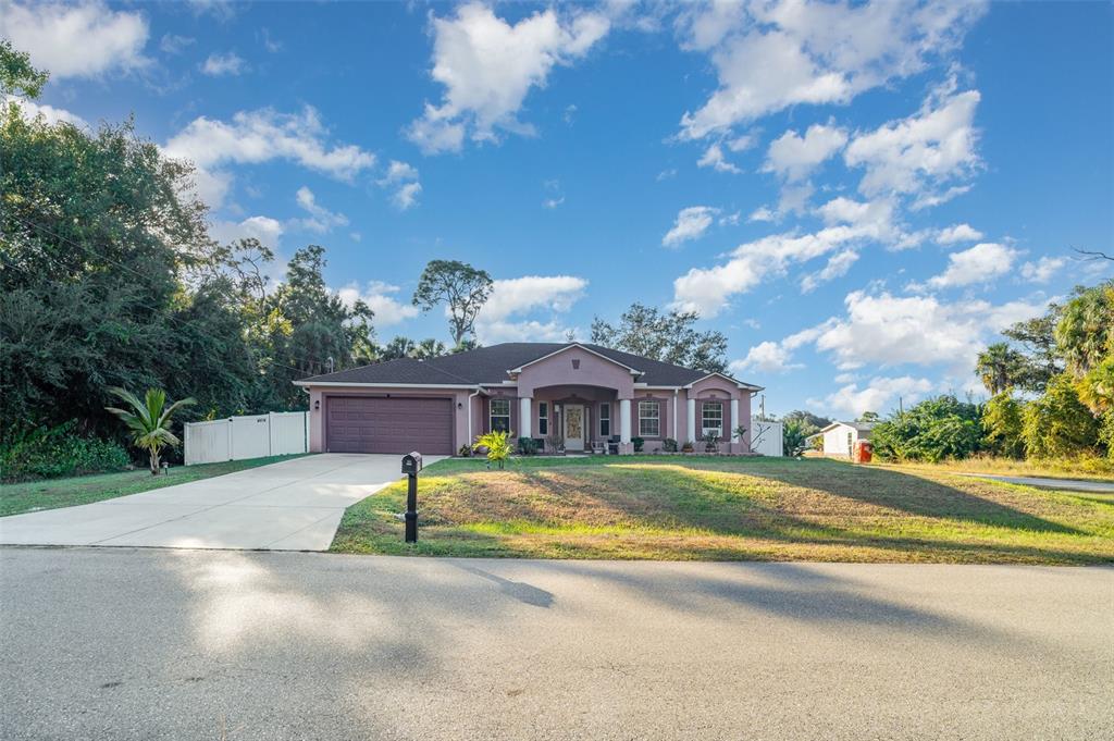 A single-story pink house with a two-car garage and a paved driveway — 249 FERDON CIRCLE, PORT CHARLOTTE, FL