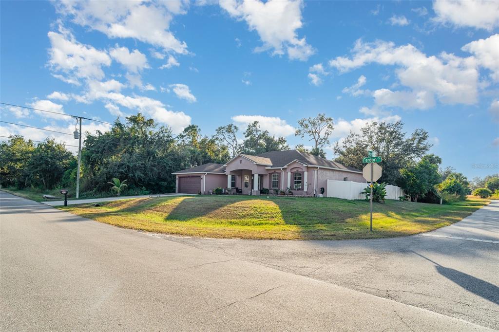 A single-story house with a tan exterior and a garage sits on a corner lot — 249 FERDON CIRCLE, PORT CHARLOTTE, FL