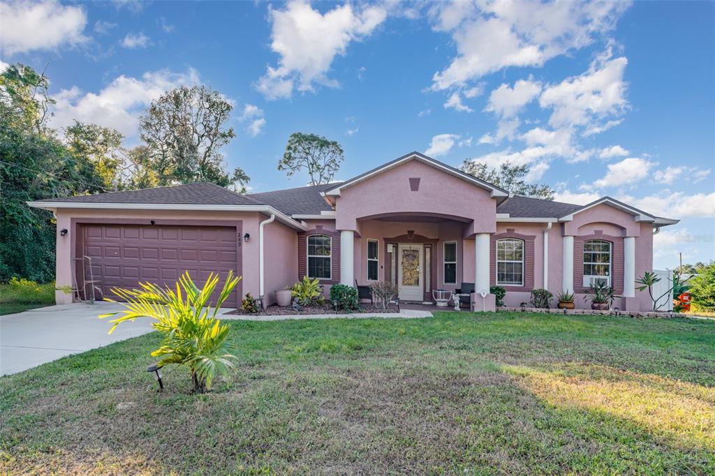 A single-story pink stucco house with a two-car garage and a covered front porch — 249 FERDON CIRCLE, PORT CHARLOTTE, FL