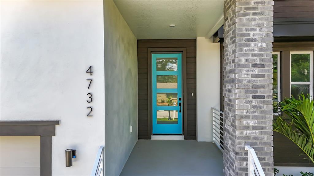 A bright blue front door is set within a covered entryway featuring white stucco walls — 4732 W WALLCRAFT AVENUE, TAMPA, FL