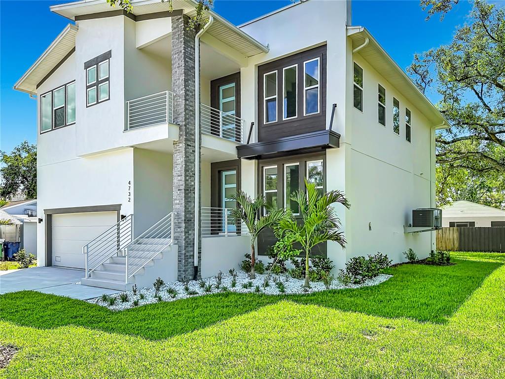 A modern two-story house with a white stucco facade, brick column, and elevated front entrance — 4732 W WALLCRAFT AVENUE, TAMPA, FL