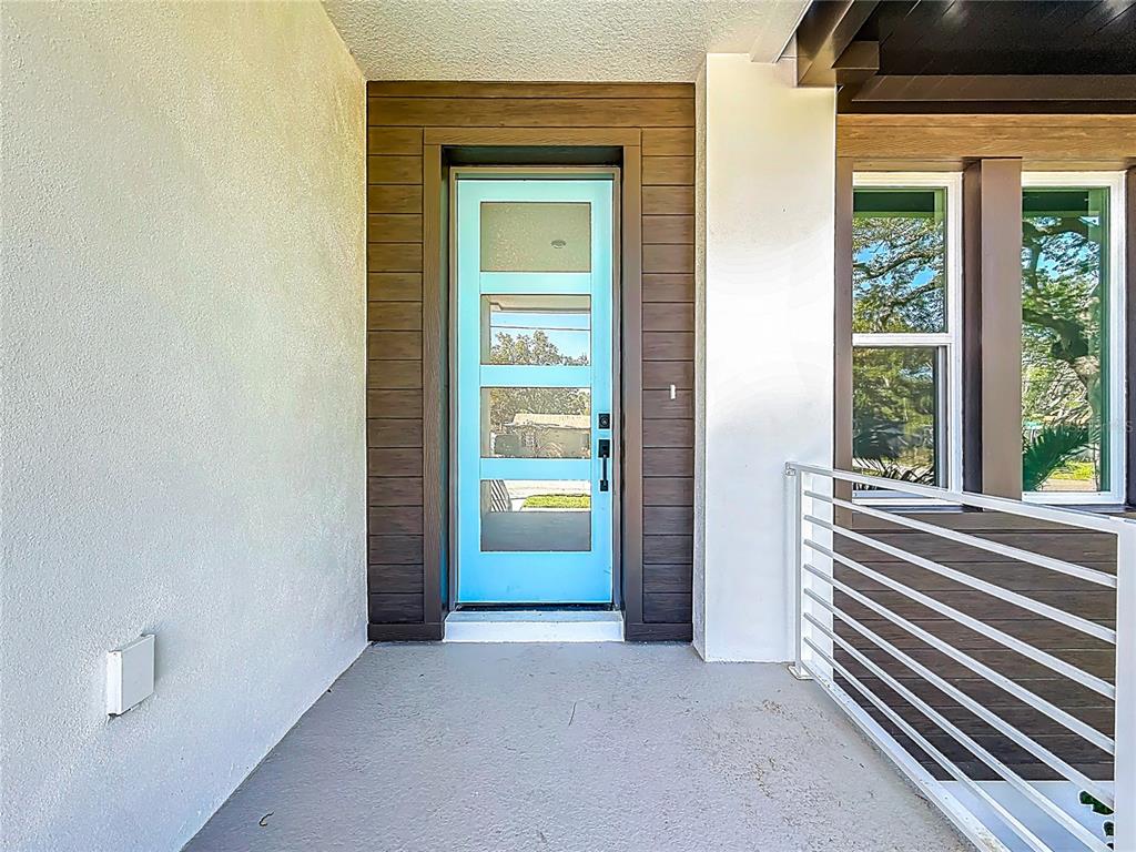 A bright blue front door is framed by dark wood siding on a covered porch — 4732 W WALLCRAFT AVENUE, TAMPA, FL