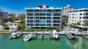 An aerial view of a waterfront apartment building with a boat dock and parked vessels — 650 GOLDEN GATE POINT UNIT 301, SARASOTA, FL