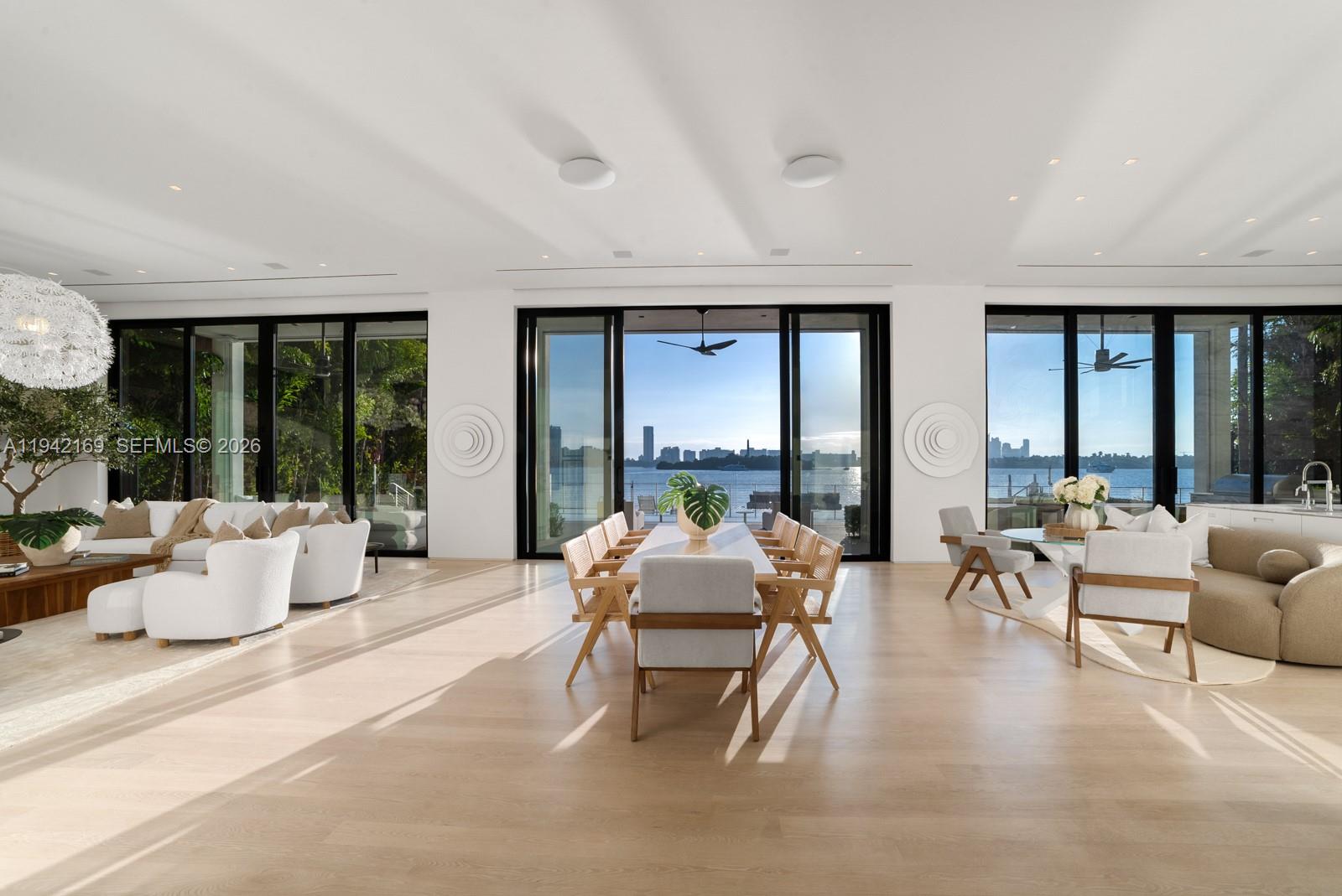 A bright, open-concept living and dining area features light wood floors and floor-to-ceiling glass doors — 33 E Dilido Dr, Miami Beach FL 33139, MIAMI BEACH, FL