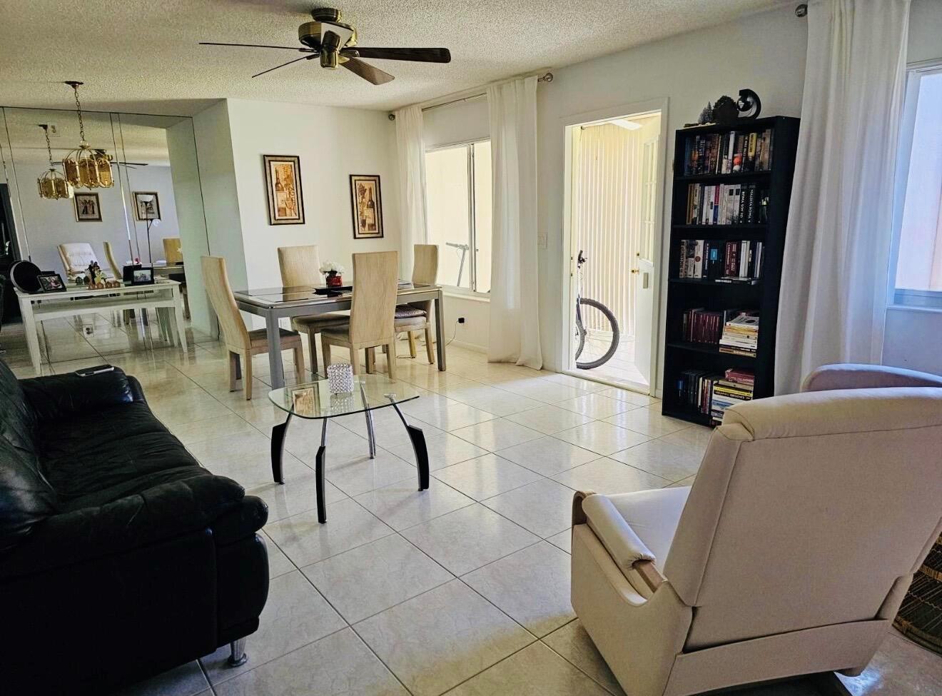 A living and dining area with tile floors, a ceiling fan, and a black bookshelf — 443 Pine Glen Lane # 2, FL 33463, FL