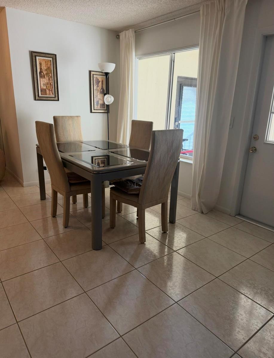 A dining area with a four-chair table, tile flooring, and a sliding glass door — 443 Pine Glen Lane # 2, FL 33463, FL