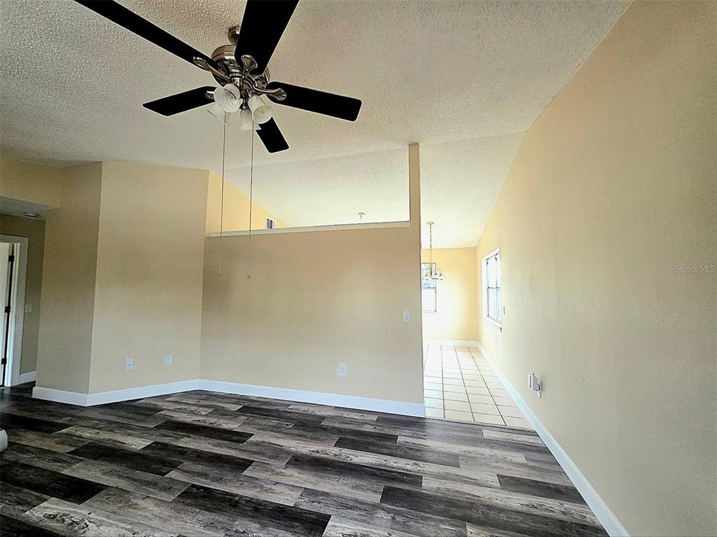 A living room features wood-look flooring, a ceiling fan, and a partial wall divider — 12091 CROSSGATE AVENUE, PORT CHARLOTTE, FL