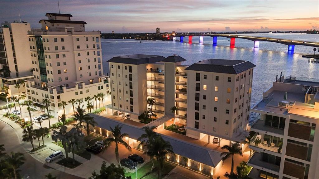 An aerial view shows apartment buildings near a bridge illuminated with red, white, and blue lights — 226 GOLDEN GATE POINT UNIT 12, SARASOTA, FL