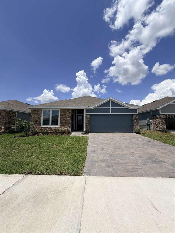A single-story house with a stone facade, blue siding, and a paved driveway — 5134 ARROWFEATHER COURT UNIT A, ST CLOUD, FL