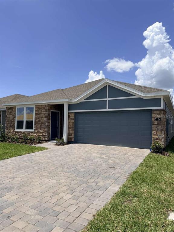 A single-story house features a stone facade, a blue-painted gable, and a paved driveway — 5134 ARROWFEATHER COURT UNIT A, ST CLOUD, FL
