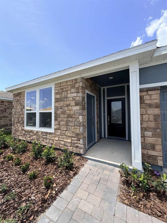 The exterior of a house features stone veneer siding, a covered entryway, and a paved walkway — 5134 ARROWFEATHER COURT UNIT A, ST CLOUD, FL