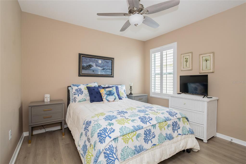 A bedroom features a bed with coastal-themed bedding, two nightstands, a dresser, and a television — 5688 SILTSTONE STREET, LAKELAND, FL