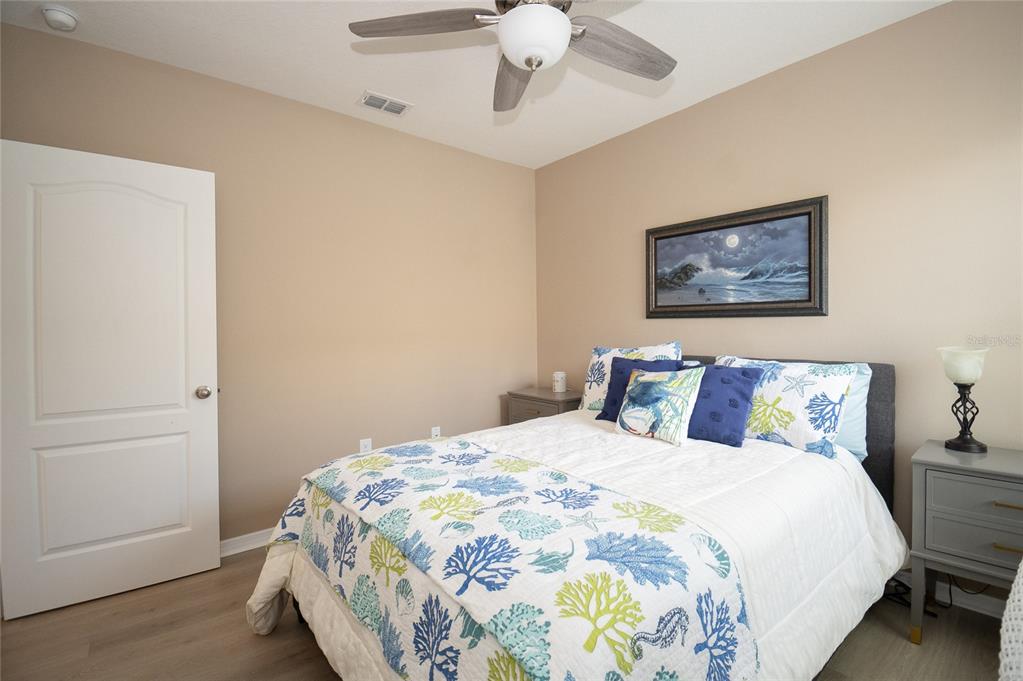 A bedroom features a bed with coastal-themed bedding, a ceiling fan, and two nightstands — 5688 SILTSTONE STREET, LAKELAND, FL