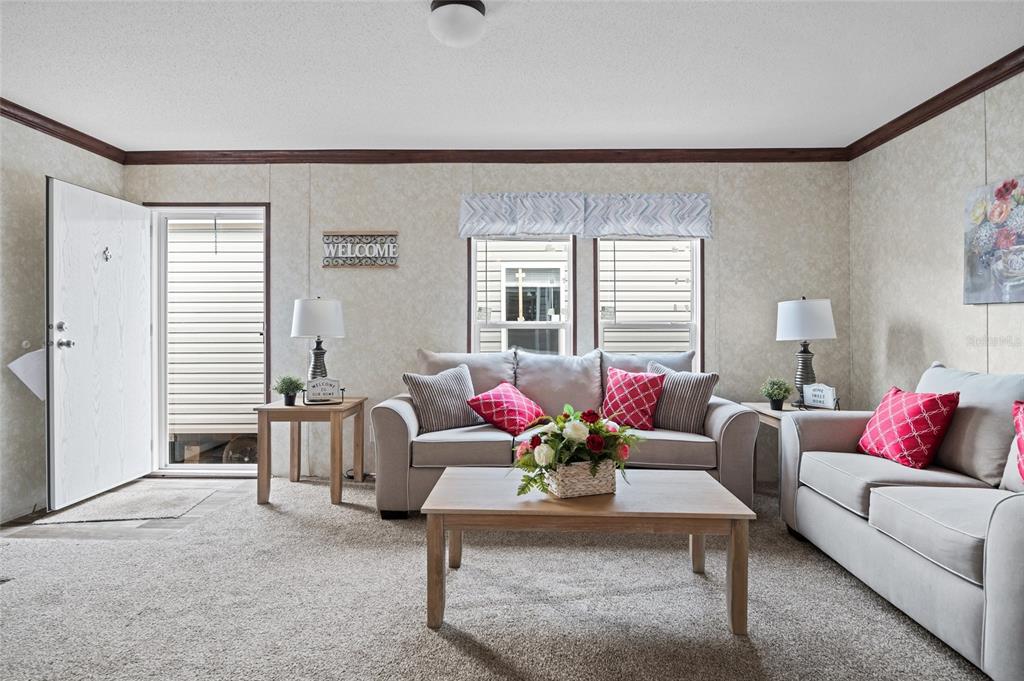 A living room features light-colored sofas, a wooden coffee table, and beige patterned wall panels — 19836 NW 280TH STREET, OKEECHOBEE, FL
