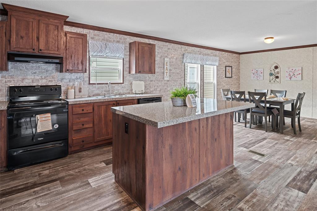 A kitchen with wood cabinets, a granite-topped island, and a dining area with a table — 19836 NW 280TH STREET, OKEECHOBEE, FL