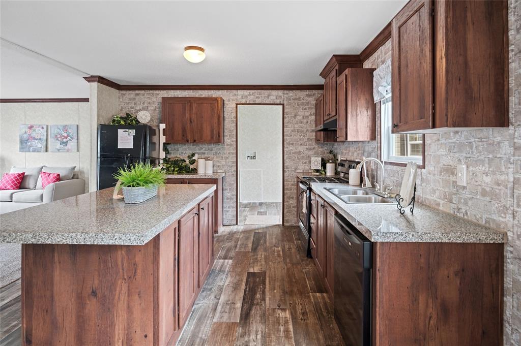 A kitchen features wood cabinets, granite countertops, a center island, and faux brick walls — 19836 NW 280TH STREET, OKEECHOBEE, FL