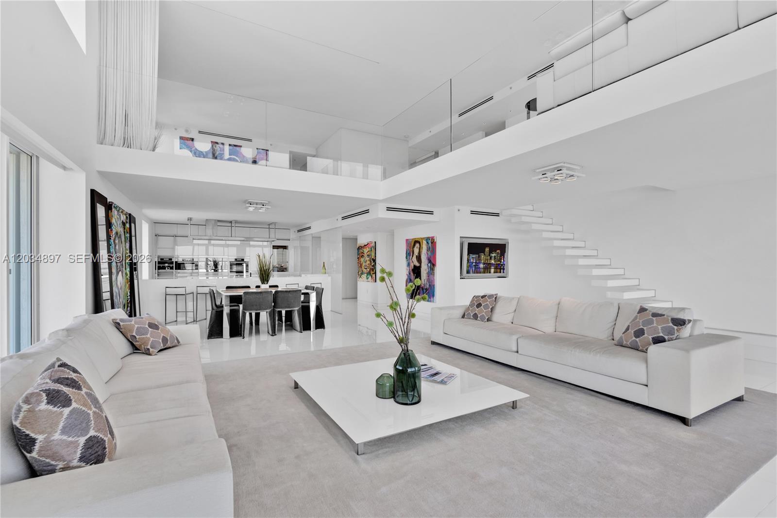 A modern, white, two-story living room features a floating staircase and a dining area — 10 Venetian Way, Miami Beach FL 33139, MIAMI BEACH, FL
