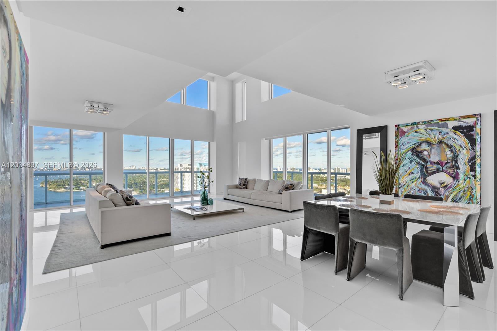 A bright, modern living and dining area features white tile floors, floor-to-ceiling windows, and artwork — 10 Venetian Way, Miami Beach FL 33139, MIAMI BEACH, FL