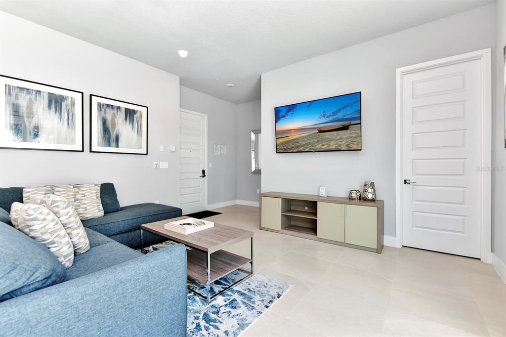 A living room features a blue sectional sofa, a television, and a media console — 7740 SANDY RIDGE DRIVE UNIT 113, REUNION, FL