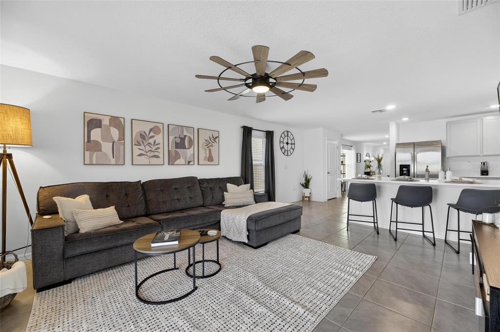 A living room with a gray sectional sofa, a ceiling fan, and an open kitchen — 3345 BLUE ESTUARY ROAD, WIMAUMA, FL