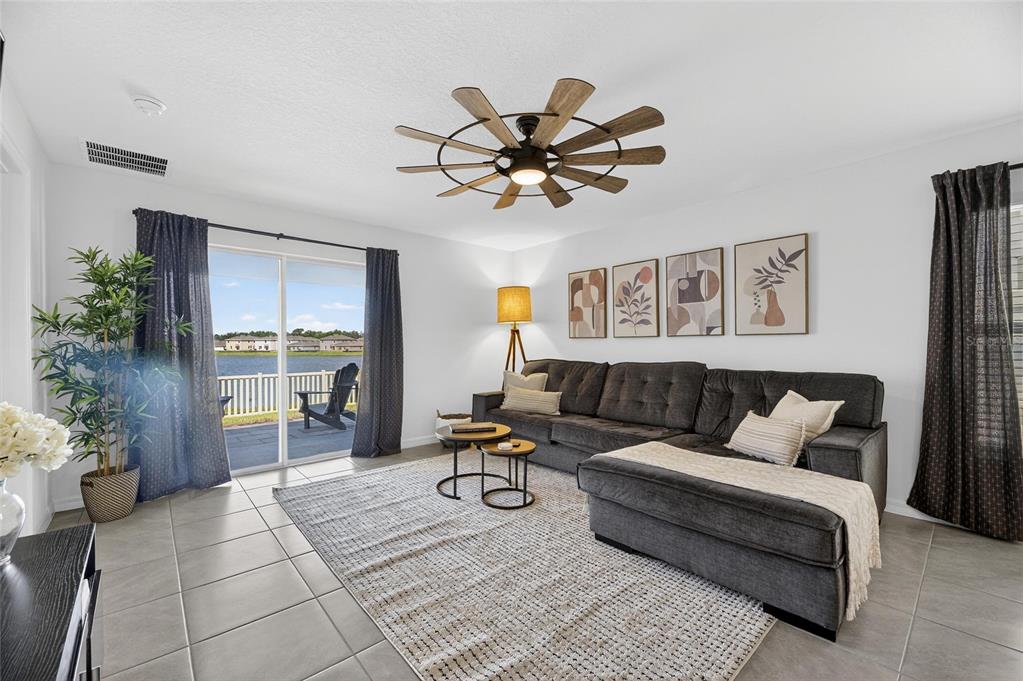 A living room features a gray sectional sofa, a ceiling fan, and sliding glass doors — 3345 BLUE ESTUARY ROAD, WIMAUMA, FL