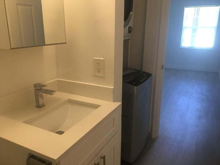 A bathroom vanity with a white countertop and sink next to a laundry closet — 407 S Lakeside Drive # A, FL 33460, FL