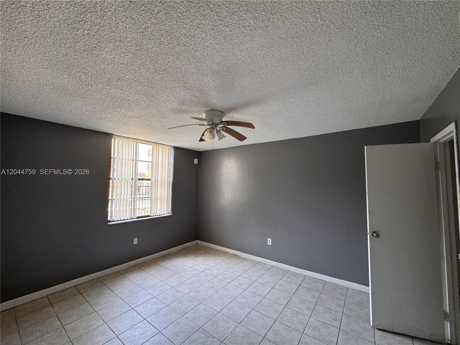 A bedroom with gray walls, a popcorn ceiling, a ceiling fan, and tiled flooring — 1756 NW 55th Ave # 101, Lauderhill FL 33313, LAUDERHILL, FL