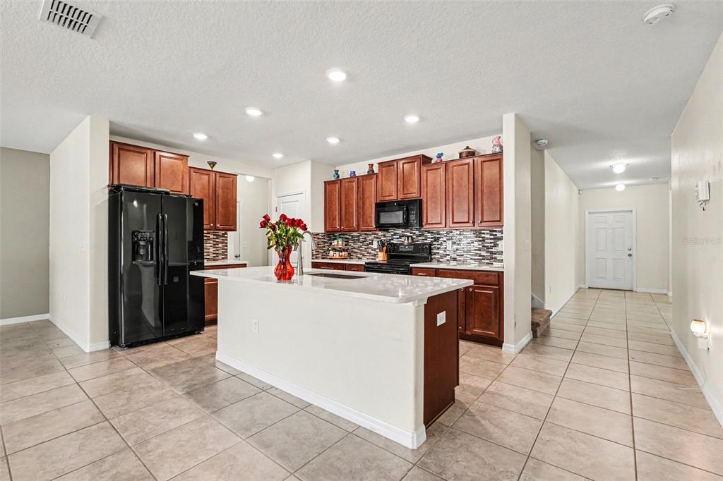 A kitchen features dark wood cabinets, a white island, and a black refrigerator — 10022 CARLOWAY HILLS DRIVE, WIMAUMA, FL