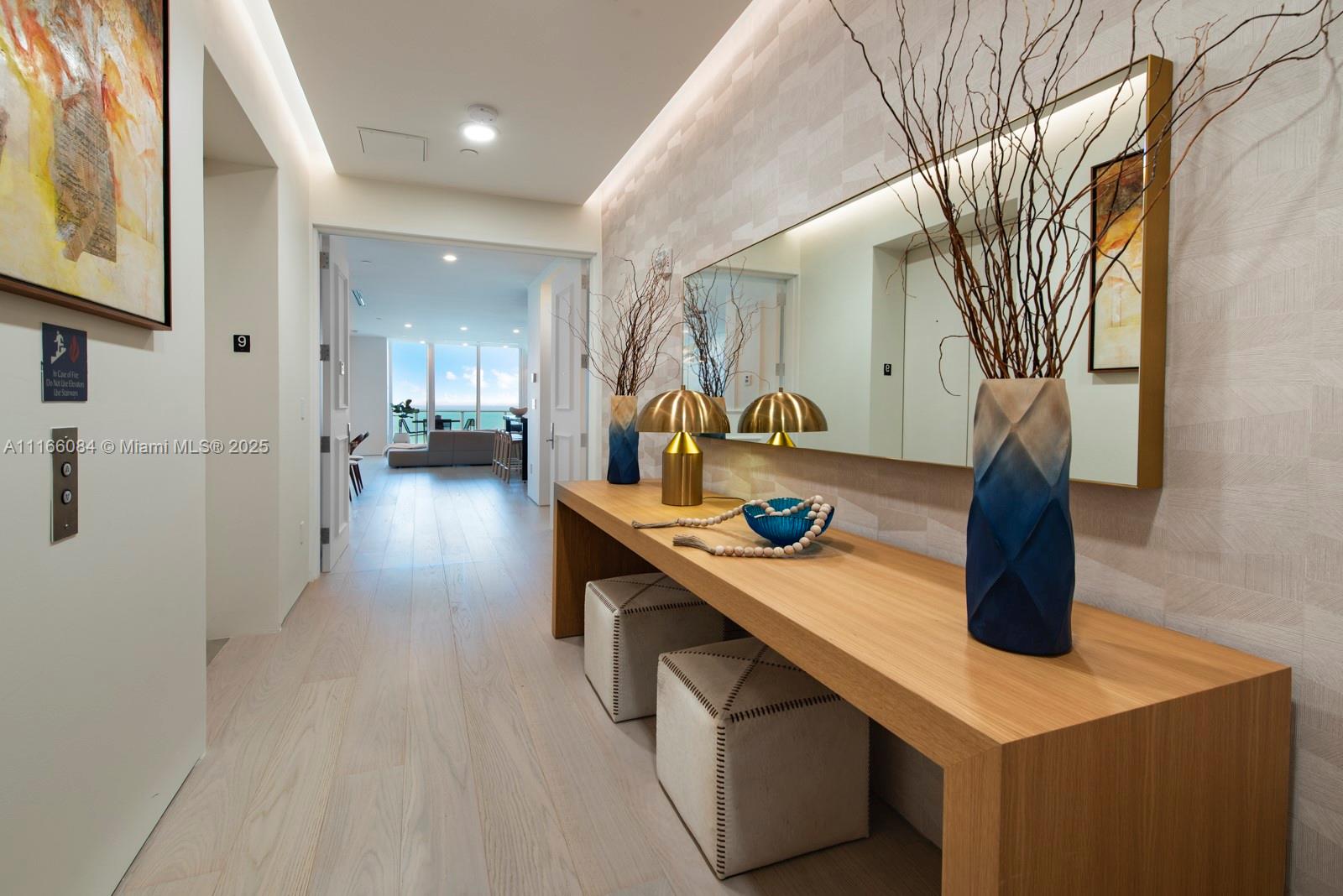 A modern hallway features a wooden console table, a large mirror, and light wood flooring — 100 S Pointe Dr # 908, Miami Beach FL 33139, MIAMI BEACH, FL