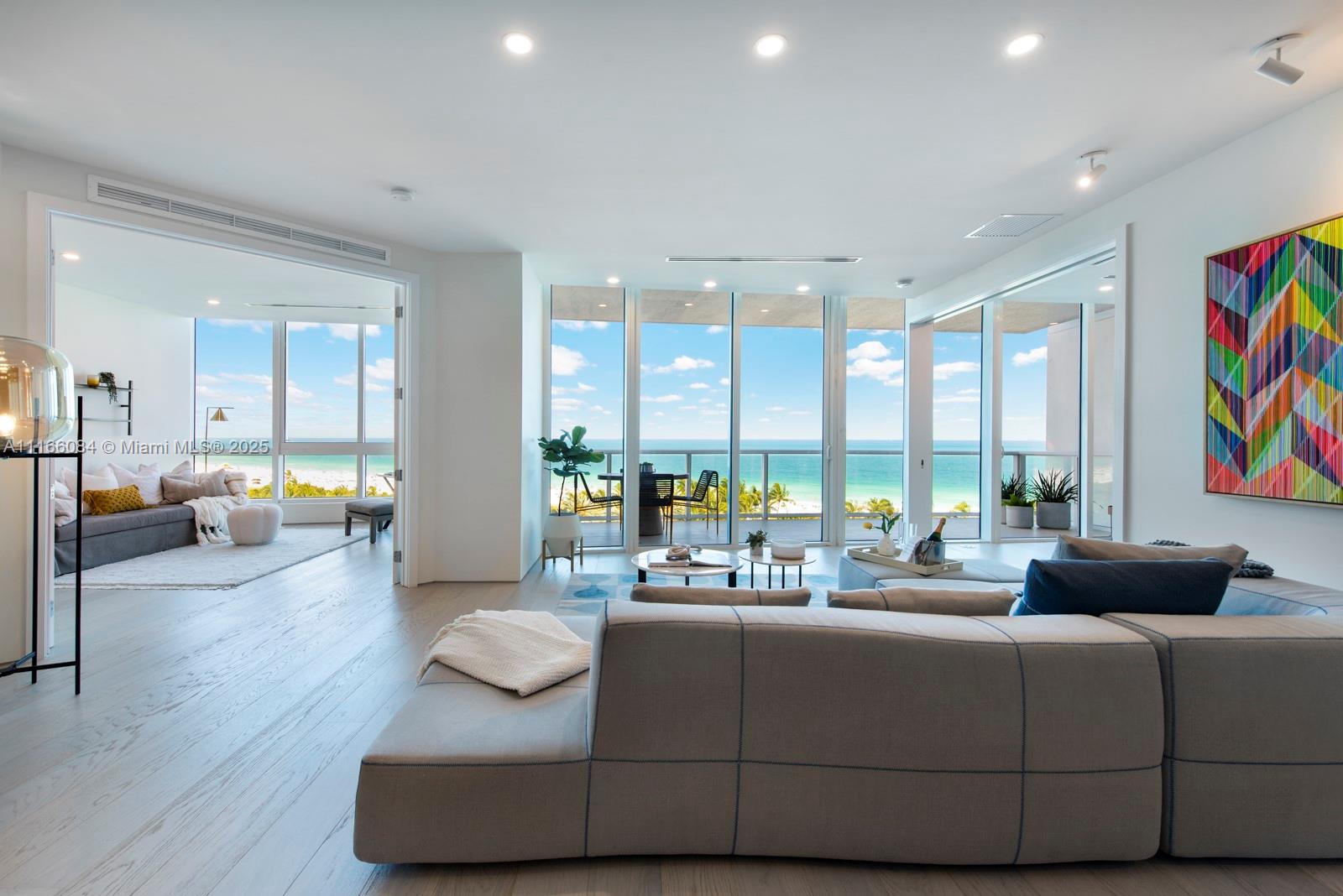 A bright, modern living room features light wood floors, a large sectional, and ocean views — 100 S Pointe Dr # 908, Miami Beach FL 33139, MIAMI BEACH, FL
