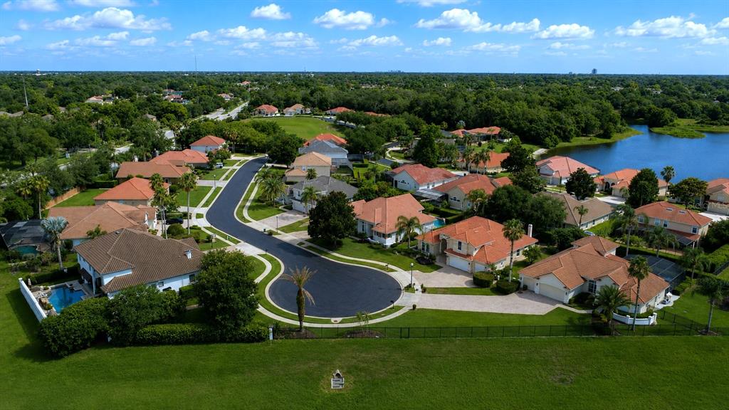 An aerial view shows a suburban neighborhood with houses, a cul-de-sac, and a nearby lake — 1954 ELKHORN COURT, LONGWOOD, FL